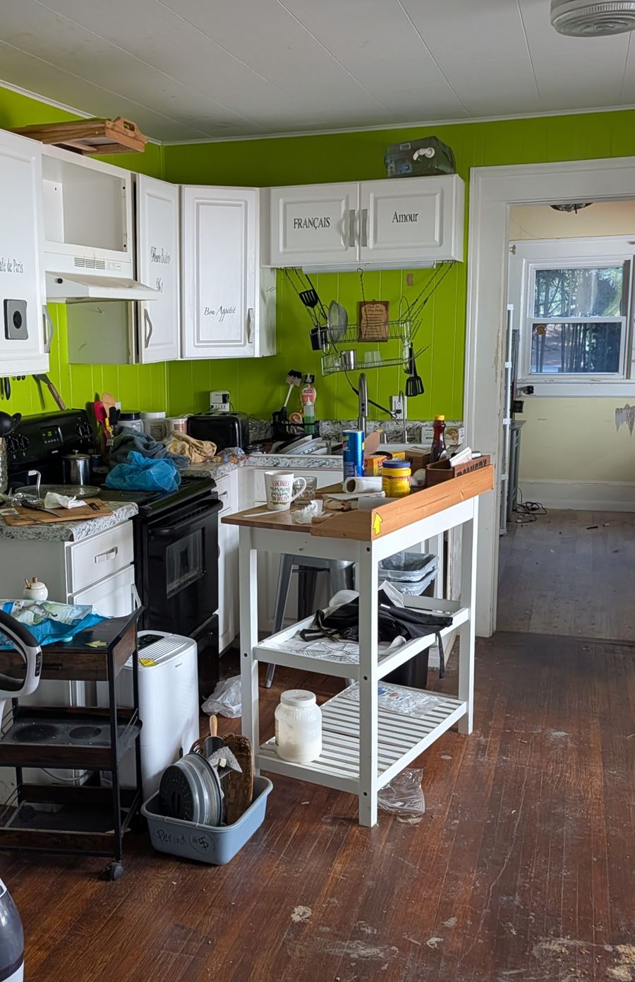 Before: a kitchen crowded with appliances, carts, and clutter during a house cleanout