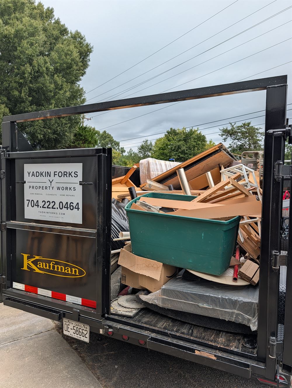 Rear view of the Yadkin Forks dump trailer loaded with lumber, cabinets, and tear-out debris on a jobsite in Davie County NC