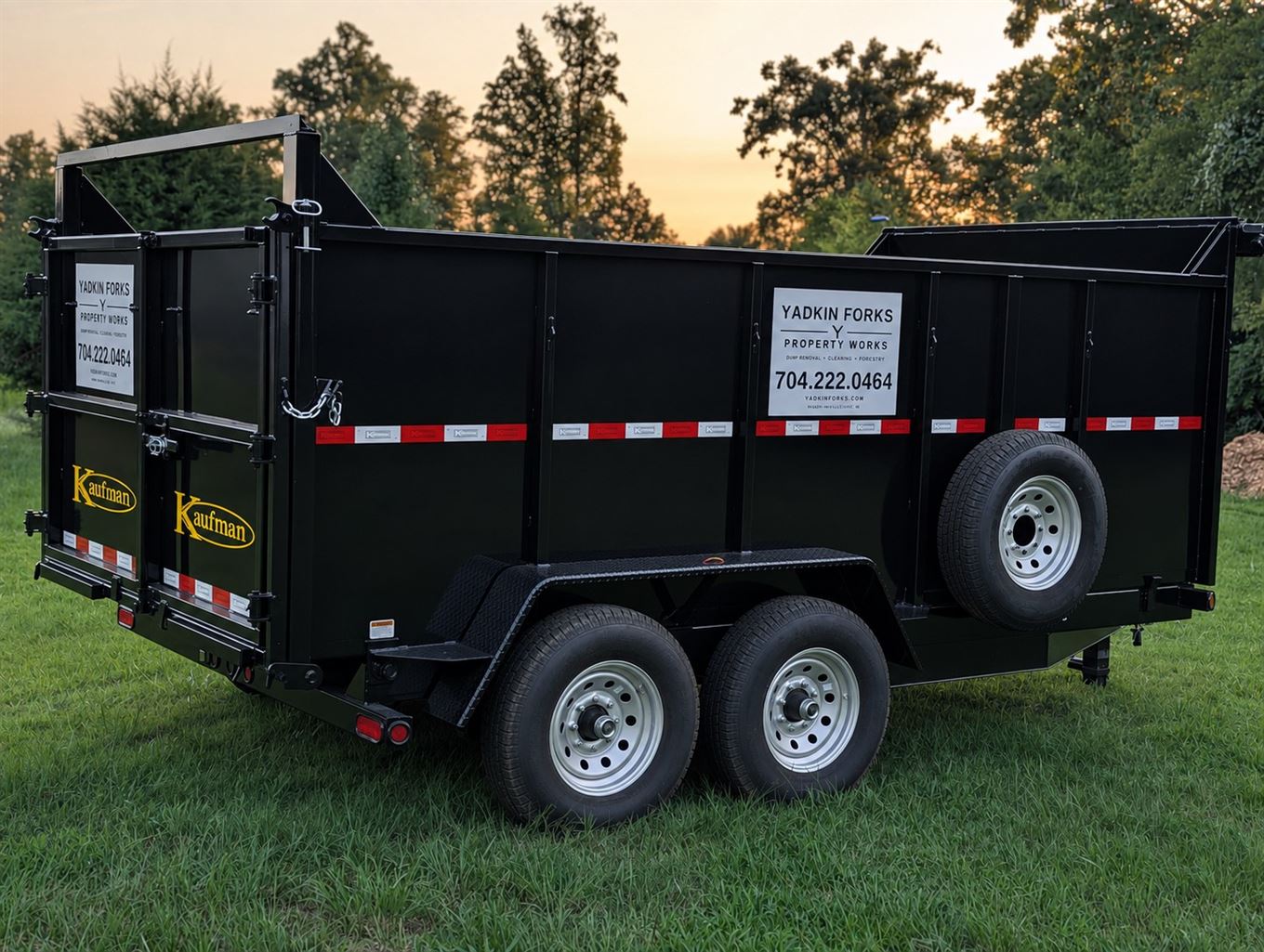 Yadkin Forks Property Works junk hauling dump trailer, a black 14 foot Kaufman with high sides, parked on grass at sunset in Mocksville, Davie County NC